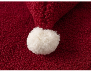 Macro shot of red fleece fabric and white pom-pom detail on girls' New Year clothes