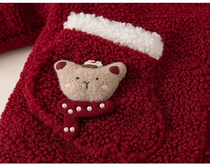 Detail of red fleece baby jacket with 3D teddy bear patch and soft plush pocket edges