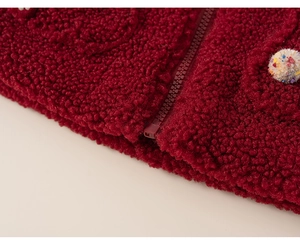 Close-up of red sherpa fleece jacket texture with zipper and pom-pom detail