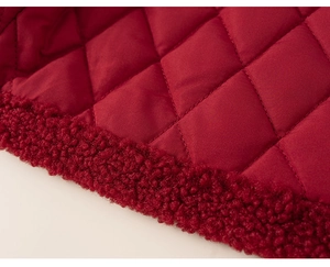 Detailed macro shot of red diamond-quilted fabric with plush lamb wool fleece trim