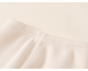 Detailed macro view of cream knitted trousers featuring elastic waistband and fine stitching