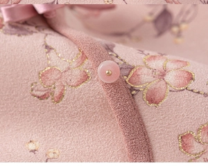 Detail eines rosa Blumenkleides mit durchscheinendem Jadeknopf und weicher Netzstruktur
