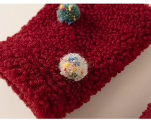 Detailed macro view of red sherpa fleece fabric sleeve with colorful decorative pom-poms