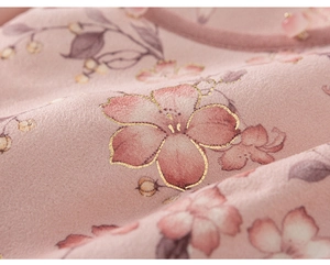 Makroansicht des rosa Blumendrucks auf weichem Samtstoff mit edlen Goldfolien-Details