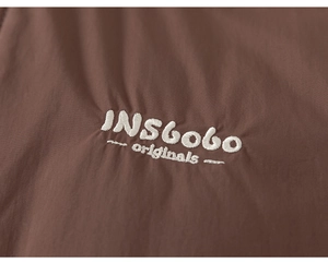 Gros plan détaillé du tissu texturé marron avec broderie blanche INSGOGO originale