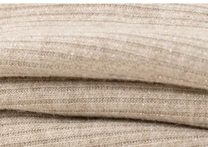 Detailed macro view of soft beige ribbed knit fabric with subtle golden glitter fibers