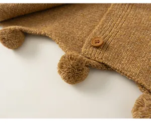 Detail of ginger yellow knit cardigan with pom-pom hem and matching resin buttons