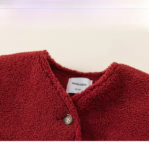 Detail of red lamb wool fabric with classic V-neck and button on kids winter jacket