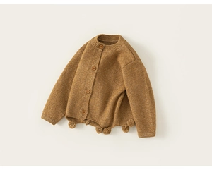 Detail of kids knit cardigan with vintage buttons and decorative pom-poms on the hem