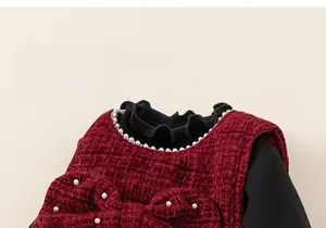 Close-up of red tweed girl dress with pearl bow and black ruffled turtleneck