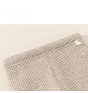 Detail of oatmeal ribbed knit waistband showing neat stitching and small woven label