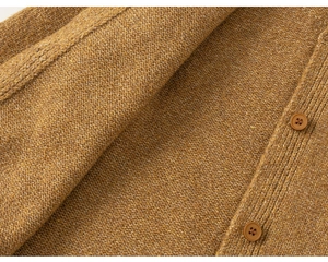 Detail of ginger yellow knit cardigan showing textured fabric and brown buttons
