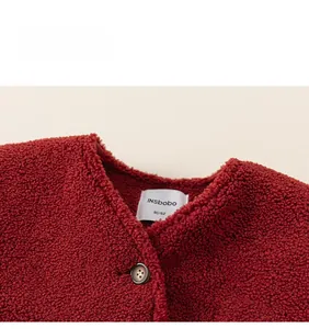 Detail of red fleece vest for kids featuring inner collar label and resin button