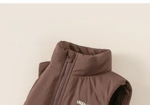Détail d'un gilet matelassé marron avec col montant et broderie de lettres blanches