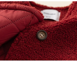 Detailed macro view of red sherpa fleece jacket with quilted lining and resin button