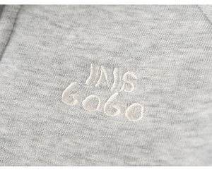 Close-up of premium light gray knit fabric with white INS GOGO embroidery detail