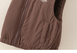 Détail d'un gilet matelassé marron avec fermeture éclair, poches et logo blanc lettré