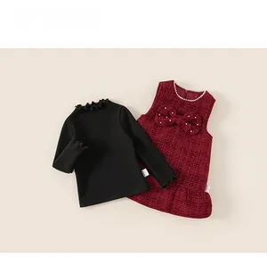 Detail of tweed dress set with large bow and pearls over black long sleeve shirt