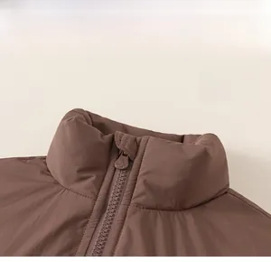 Gros plan détaillé du gilet rembourré pour enfant marron foncé avec col montant et zip