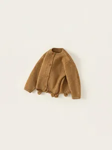 Kids knitted cardigan in camel brown with decorative pom-poms on the hem, autumn style