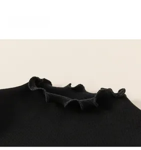 Detail of black ribbed knit girls top with elegant ruffle collar design on beige background