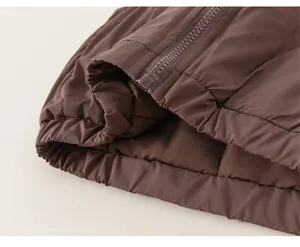 Gros plan de l'ourlet de la veste marron avec texture matelassée et fermeture éclair