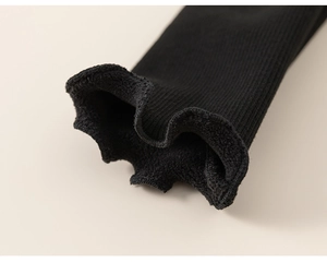 Detailed close-up of girls' black rib-knit thermal sleeves with soft fleece lining and ruffled edges