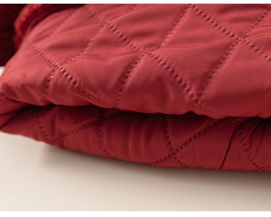 Detail of red diamond quilted fabric with intricate stitching for winter children outfit
