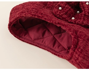 Detailed close-up of red tweed fabric texture with pearl decorations and quilted lining