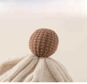 Macro shot of a handmade brown knitted ball detail on a cream wool knit beanie