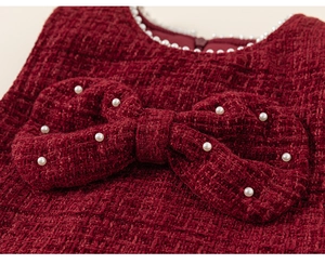 Detail of red tweed dress with white pearl collar and a large pearl bow accent