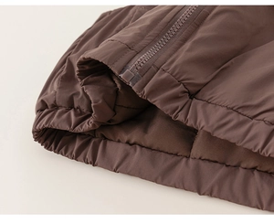 Détail d'un gilet matelassé marron foncé pour enfant avec fermeture éclair et coutures