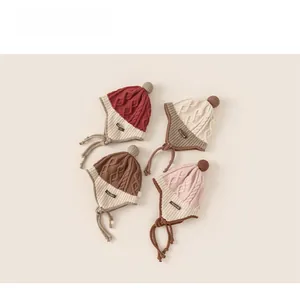Detailed view of knitted baby hats with pom-poms and braided earflaps in four colors