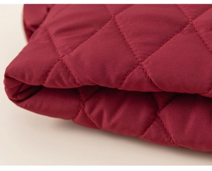 Close-up of girls' wine red quilted jacket featuring classic diamond stitching detail