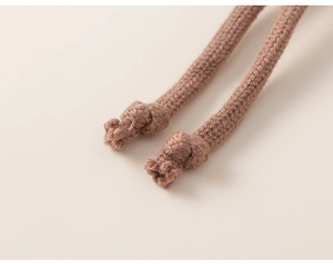 Detailed close-up of knitted drawstring texture and fine craftsmanship on a winter hat