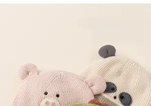 Close-up of soft knit kids hats with cute cartoon animal ears in pink and green