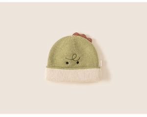 Detail of olive green knit hat with red dinosaur fins and cute cartoon face embroidery