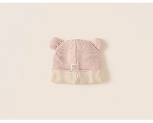 Detail of pink and beige knitted baby hat with cute 3D bear ears and soft texture