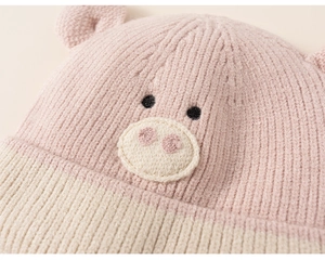 Close-up of pink knitted baby hat with cute 3D ears and pig embroidery details
