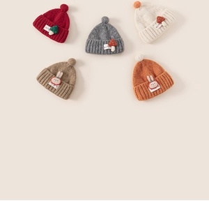 Flat lay of colorful knit toddler hats with cartoon patches and soft decorative pom-poms