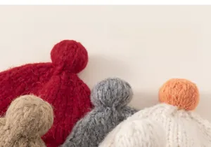 Macro shot showing plush knit pompoms on toddler hats in various warm winter colors
