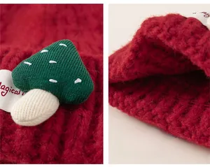 Close-up of red knitted baby hat with 3D mushroom patch and ribbed elastic hem detail