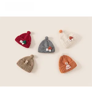 Flat lay of five colorful children knit earflap hats with cute 3D charms and pom-poms