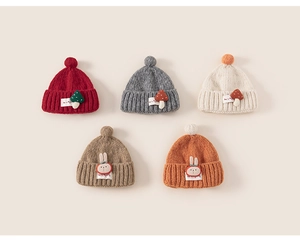 Detail of five colorful knit beanies featuring plush pom-poms and cute mushroom patches