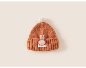 Detail of orange knit baby hat showing thick texture and cute white rabbit patch