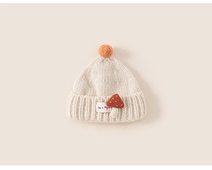 Close-up of knit texture and cute mushroom patch on the cream baby winter hat