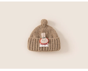 Close-up of brown knit baby hat featuring a 3D bunny patch and soft pom-pom detail