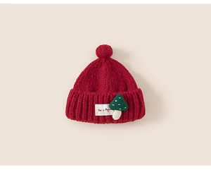 Close-up of red knit hat for kids with a green mushroom patch and soft pompom detail
