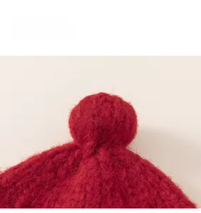Close-up of fluffy red pom-pom detail on a warm knitted baby winter hat