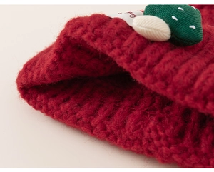 Detailed macro view of dark red chunky knit texture with a 3D festive tree applique